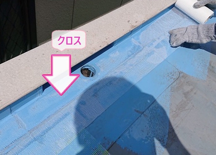 屋上防水の改修工事で端部にクロスを貼っている様子