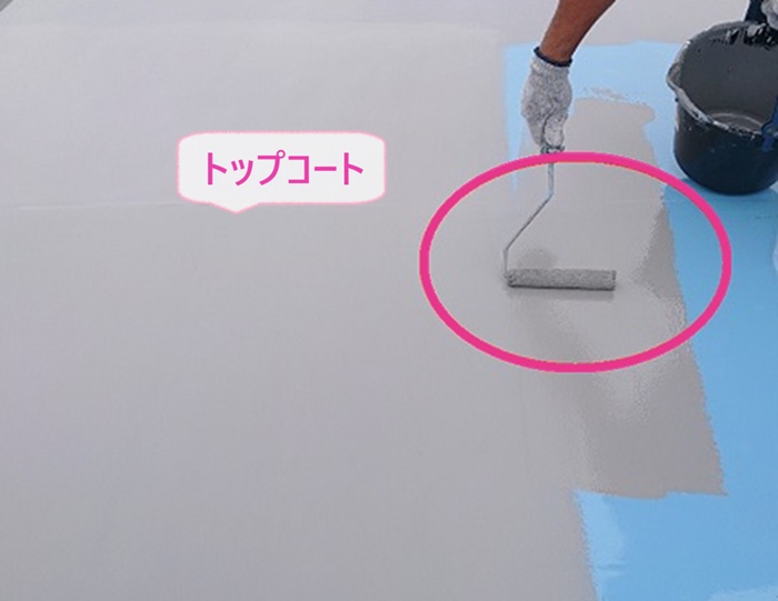屋上防水の改修工事で仕上げとなるトップコートを塗っている様子