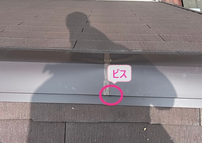 台風で傷んだスレート屋根の部分補修で棟板金をビスで固定している様子