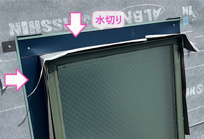 トップライトのあるスレート屋根の重ね張りで水切りを取り付けている様子