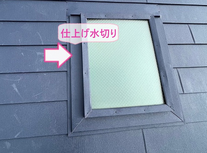 トップライトのあるスレート屋根の重ね張りで仕上げ水切りを取り付けている様子