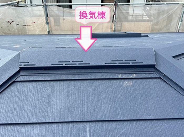 トップライトのあるスレート屋根の重ね張りで換気棟を取り付けている様子