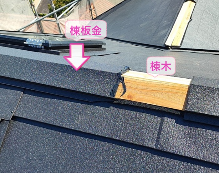 トップライトのあるスレート屋根の金属重ね張りで棟木と棟板金を取り付けている様子