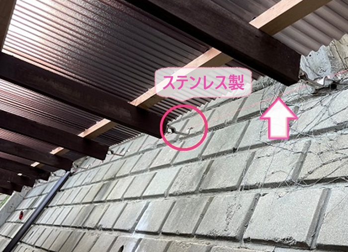 破損した雨樋の取り替えで新しいステンレス製の固定金具を取り付けている様子