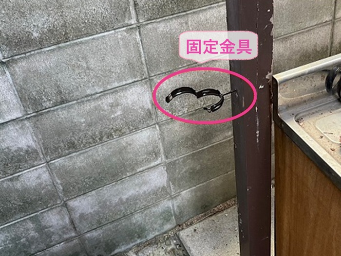 破損した雨樋の取り替えで新しい竪樋の固定金具を取り付けている様子