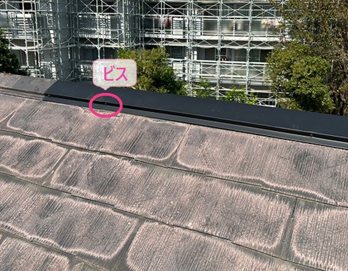 風害を受けた平型スレート屋根の局所補修で棟板金をビスで固定している様子