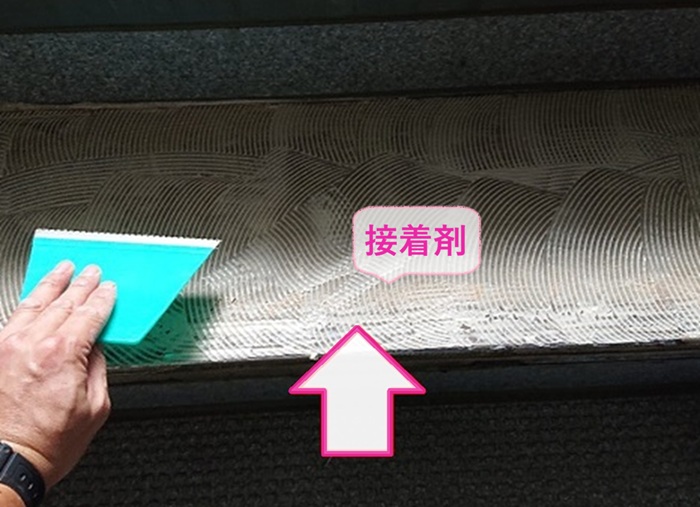 共用階段の部分修繕でヘラや小手を使用して接着剤を塗っている様子