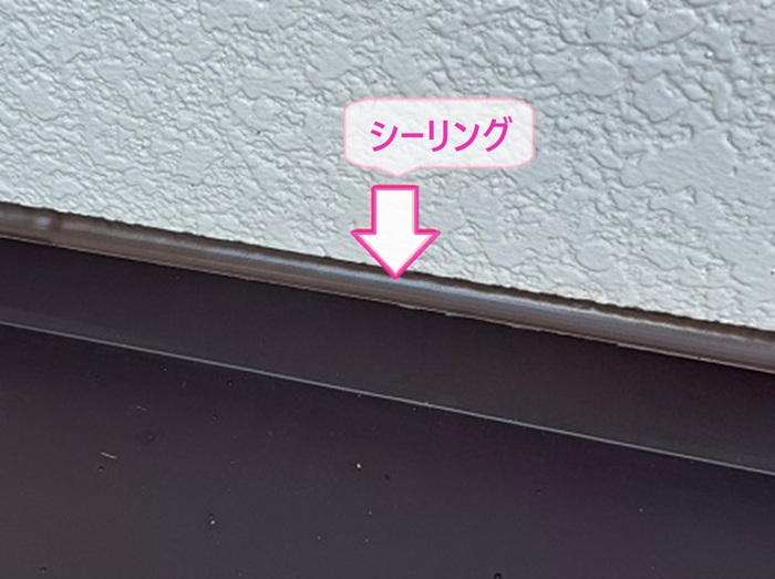 玄関庇の板金カバー工事で壁際にシーリングを打設している様子