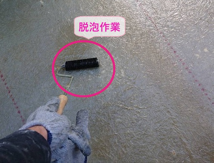 バルコニー防水工事でガラス繊維マットの気泡を脱泡している様子