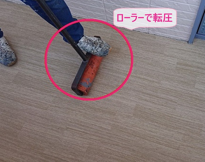 集合住宅の共用通路の改修で防滑シートをローラーで転圧している様子