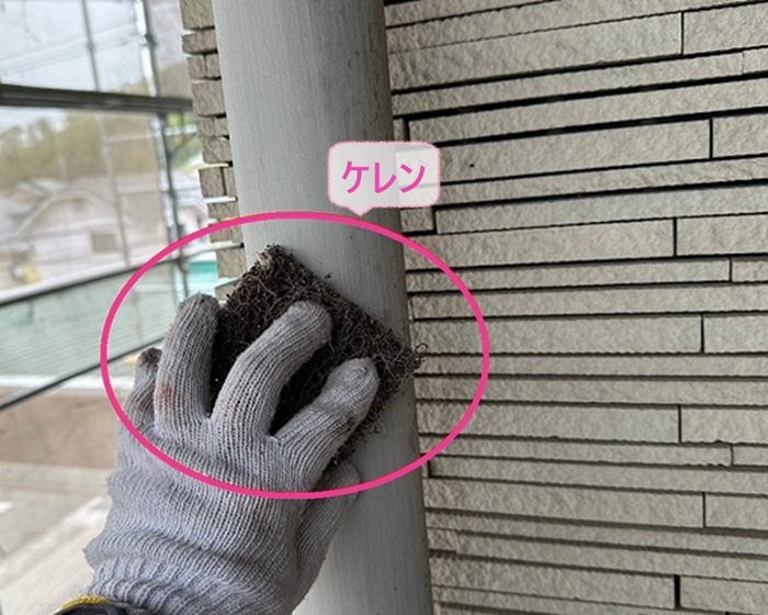 テナント建物の鼻隠しの部分塗装で竪樋をケレンしている様子