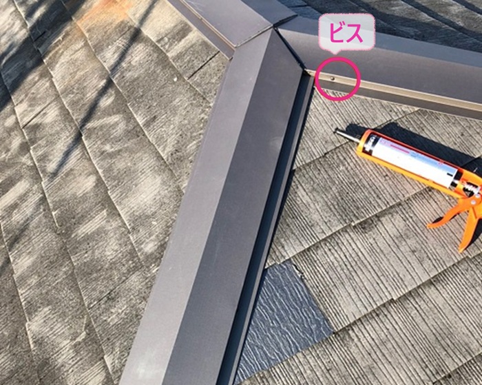 3階建て平型スレート屋根の補修工事で棟板金をビスで固定している様子