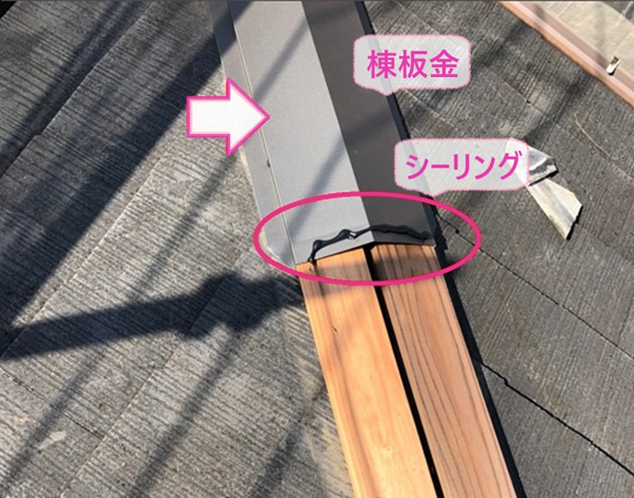 3階建て平型スレート屋根の補修工事で新しい棟板金を取り付けている様子