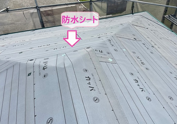 層間剝離する平型スレート屋根に防水シートを貼っている様子