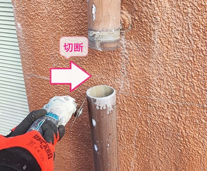 店舗建物の割れてる雨樋を部分的に切断している様子