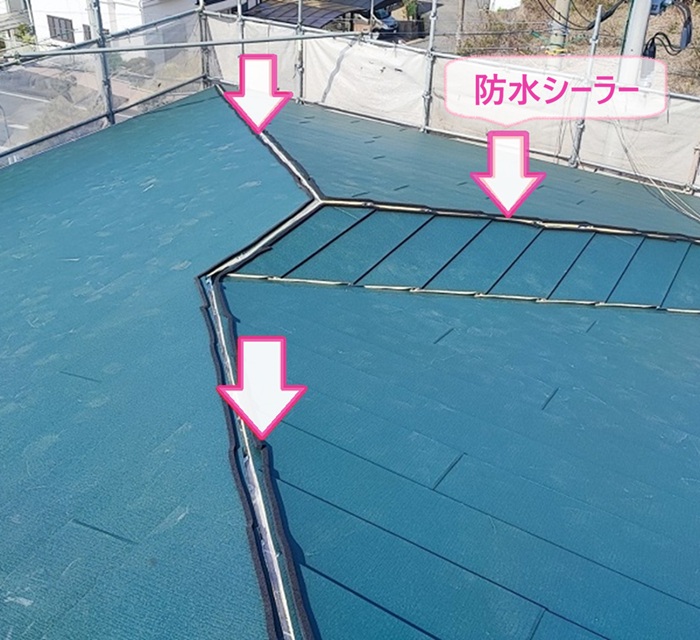 店舗建物の屋根改修工事で棟の部分に防水シーラーを貼っている様子