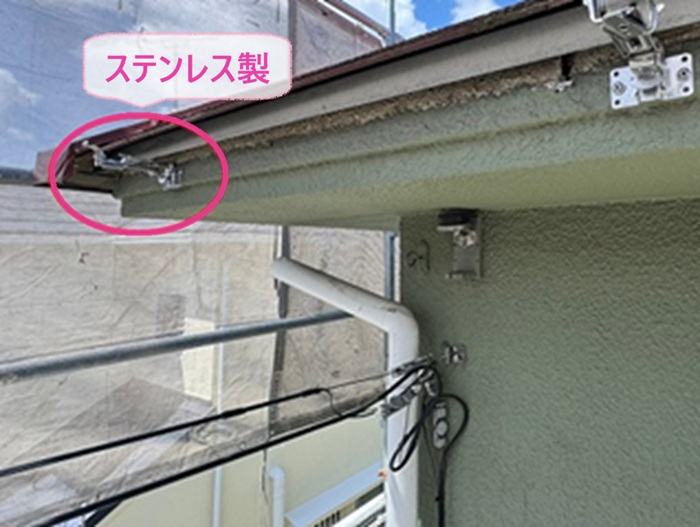 戸建て住宅の雨どい交換でステンレス製の固定金具を取り付けている様子