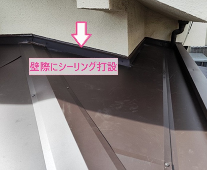 玄関庇のカバー工事で壁際にシーリングを打設している様子