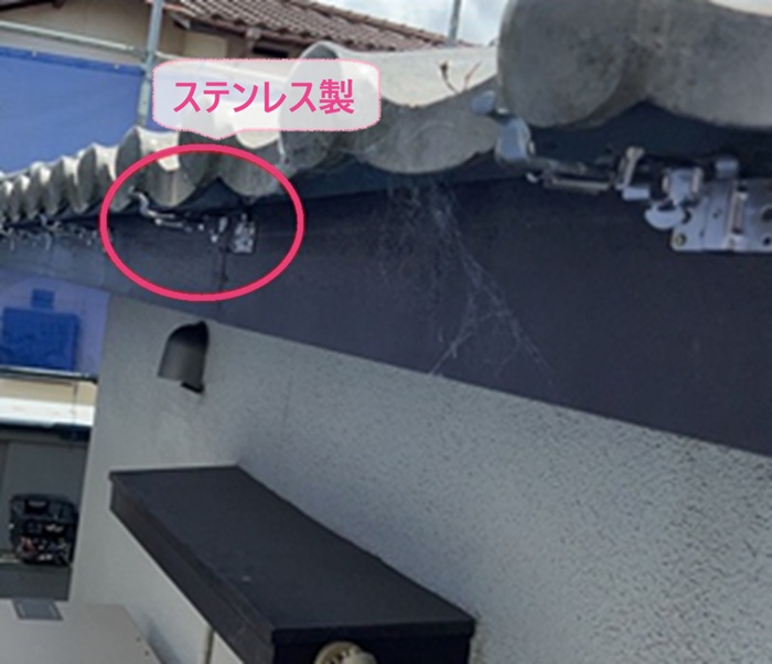 古い半円型雨どいの交換で新しくステンレス製の固定金具を都営るけている様子