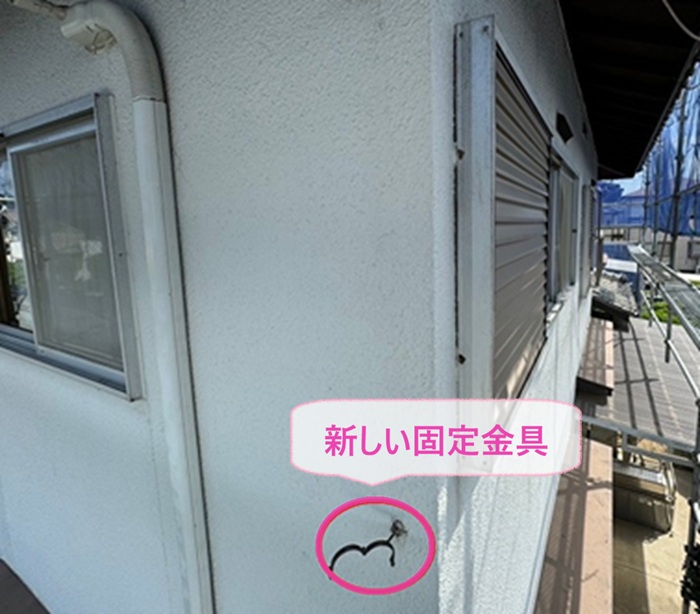 宝塚市の雨樋交換で新しい竪樋の固定金具を取り付けている様子