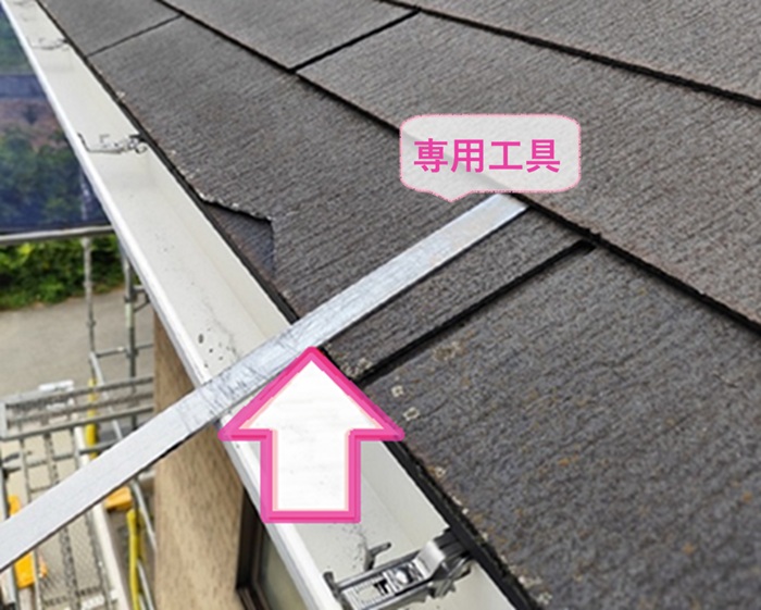 屋根差し替えで割れているスレートの固定釘を専用工具で抜いている様子