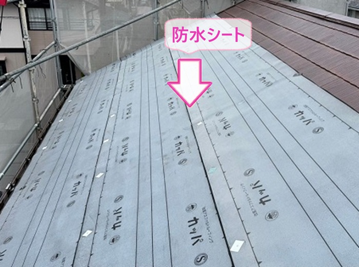 既存のスレートを覆う改修工事で防水シートを貼っている様子