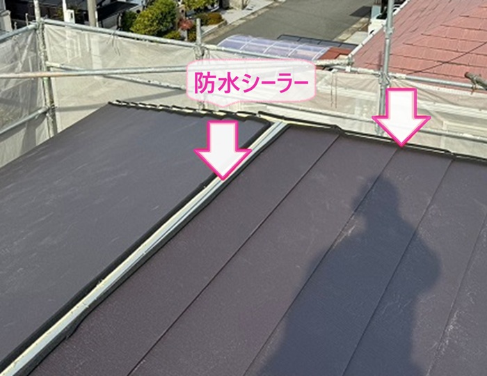 既存のスレートを覆う改修工事で棟の部分に防水シートを貼っている様子