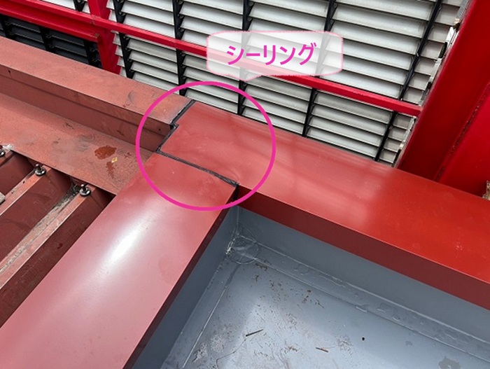 テナントビルの陸屋根金属改修で笠木の端部をシーリングで止水処理している様子