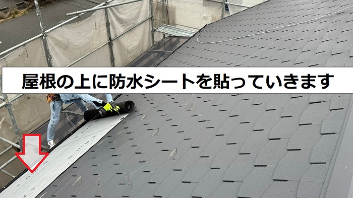 2階建ての屋根台風対策で割れの多いスレート屋根の上に防水シートを貼っている様子
