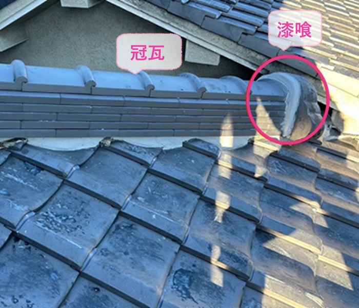 屋根頂部の部分積み直しで冠瓦を取り付けて鬼瓦まわりに漆喰を塗っている様子