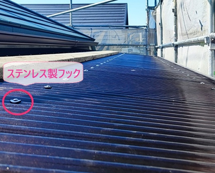 バルコニー屋根の張り替えでポリカ波板をステンレス製フックで固定している様子