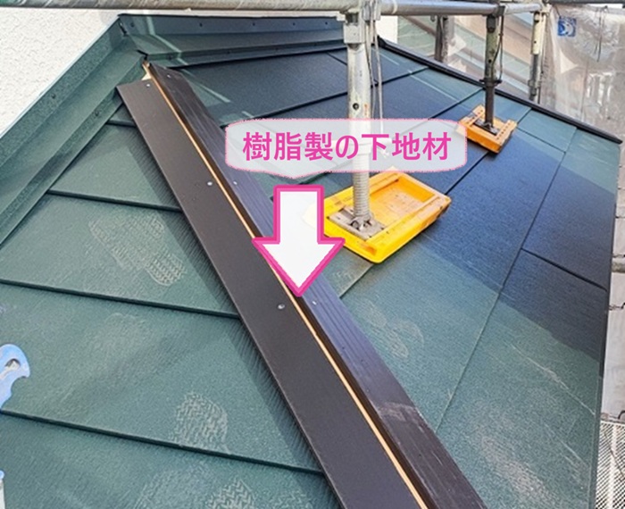 老朽化した化粧スレート屋根の重ね葺きで棟に樹脂製の下地材を取り付けている様子