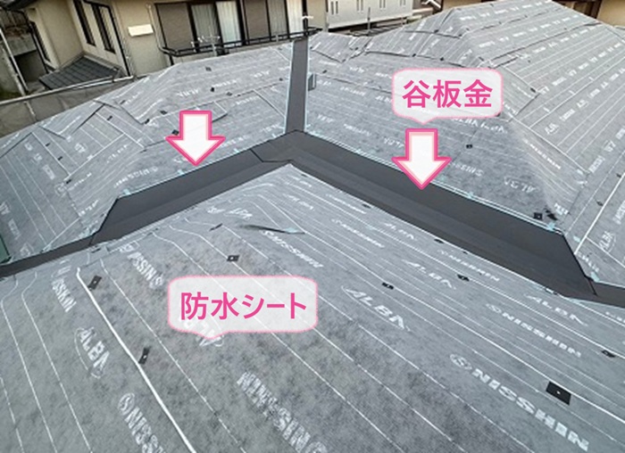 屋根重ね葺き工事で防水シートを貼って谷板金を取り付けている様子