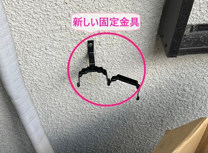 西宮市の雨樋交換で竪樋の新しい固定金具を取り付けている様子
