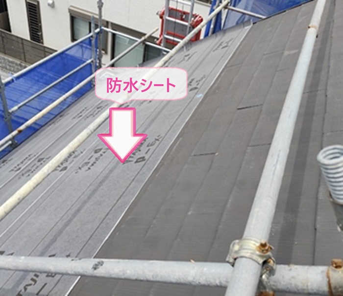 急傾斜な化粧スレートの重ね葺き改修で防水シートを貼っている様子