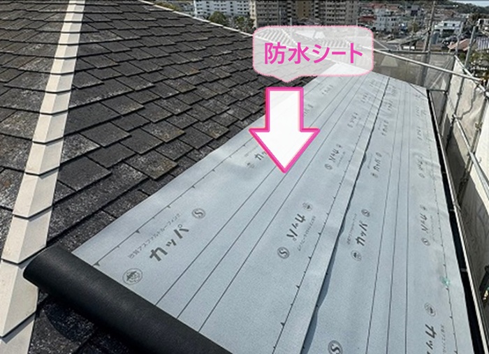 寄棟住宅の屋根重ね葺き工事で防水シートを貼っている様子