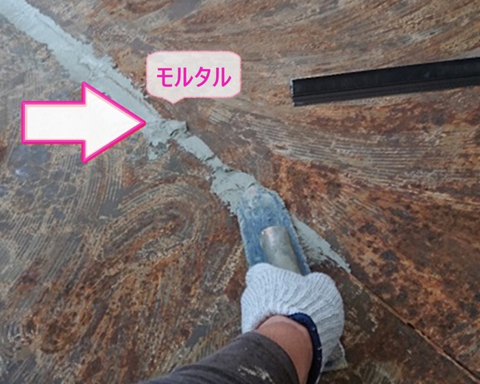 集合住宅の共用階段の目地をモルタルで埋めている様子