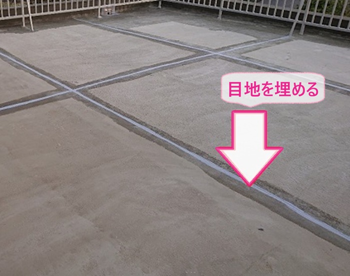 劣化したベランダ床目地の防水対策で目地をコーキングで埋めている様子