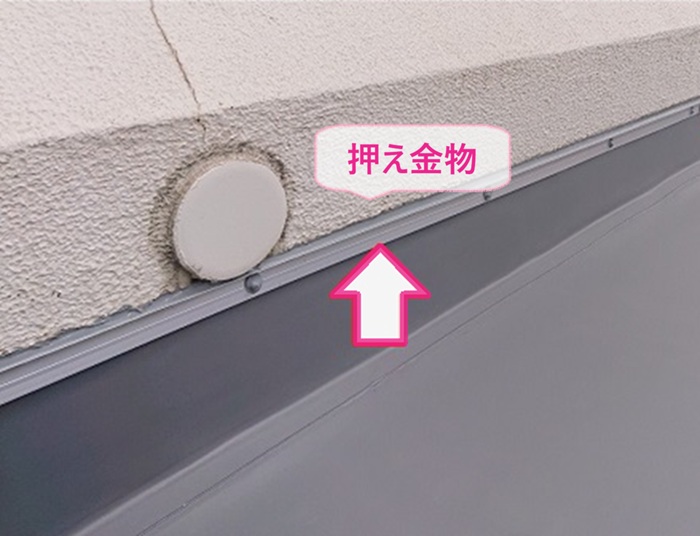 店舗ベランダ防水改修で立ち上がり部分に新しい押え金物を取り付けている様子