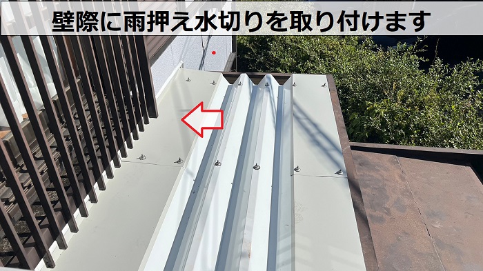 雨漏りを解消するための折板屋根カバー工事で壁際に雨押え水切りを取り付けている様子