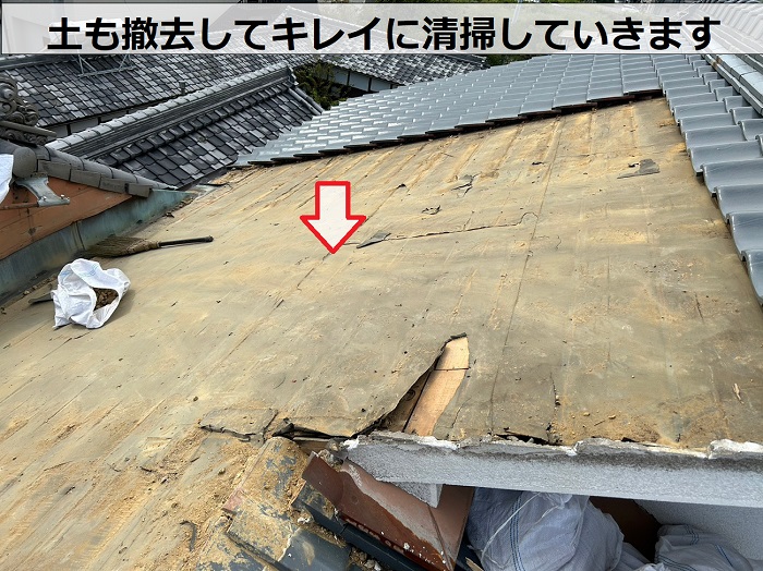 瓦屋根の部分的な葺き直し工事で屋根上を清掃している様子