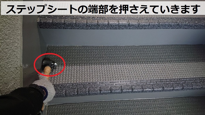 尼崎市のハイツで共用階段のステップシートを転圧している様子