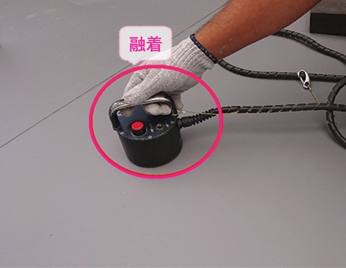 ビルの陸屋根防水の改修で塩ビシートを機械で融着している様子