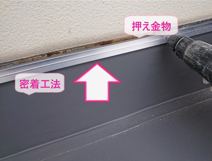 ビルの陸屋根防水の改修で立ち上がり部分は密着工法で押え金物を取り付けている様子