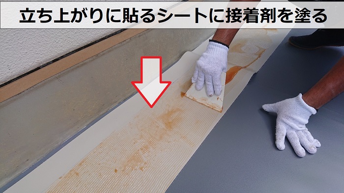 神戸市長田区でビル屋上の防水工事で立ち上がり部分のシート防水に接着剤を塗っている様子