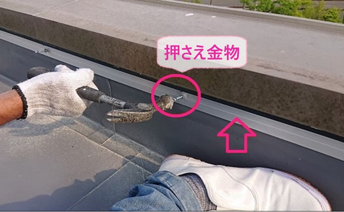 陸屋根の立ち上がりに押さえ金物を取り付けている様子