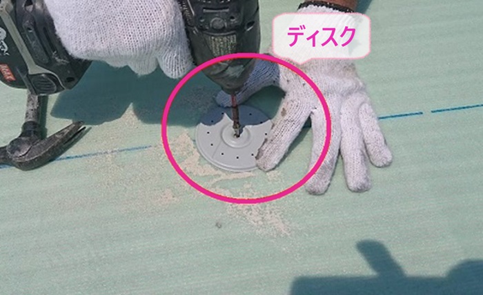 陸屋根の塩ビシート防水機械固定工法でディスクを取り付けている様子