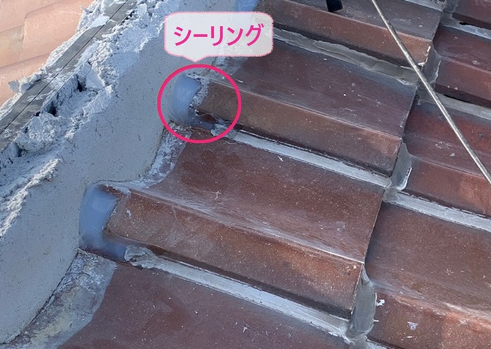 瓦屋根の部分修理で瓦の隙間をシーリングで補修している様子