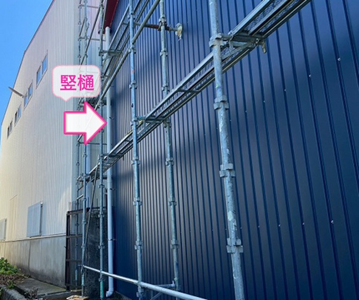 工場の樋リフォームで新しい竪樋を取り付けている様子