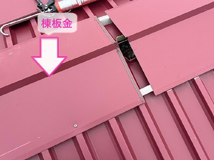 工場屋根の重ね葺きの仕上げに棟板金を取り付けている様子